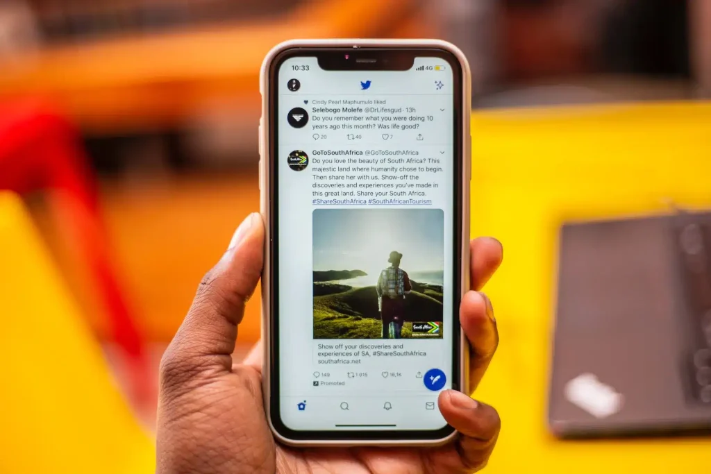 Main tenant un smartphone avec sur l'écran l'accueil de X (Twitter)