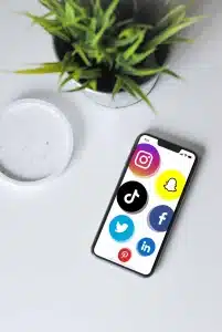 Smartphone affichant les icônes de réseaux sociaux populaires (Instagram, Snapchat, TikTok, Facebook, Twitter, LinkedIn, Pinterest)