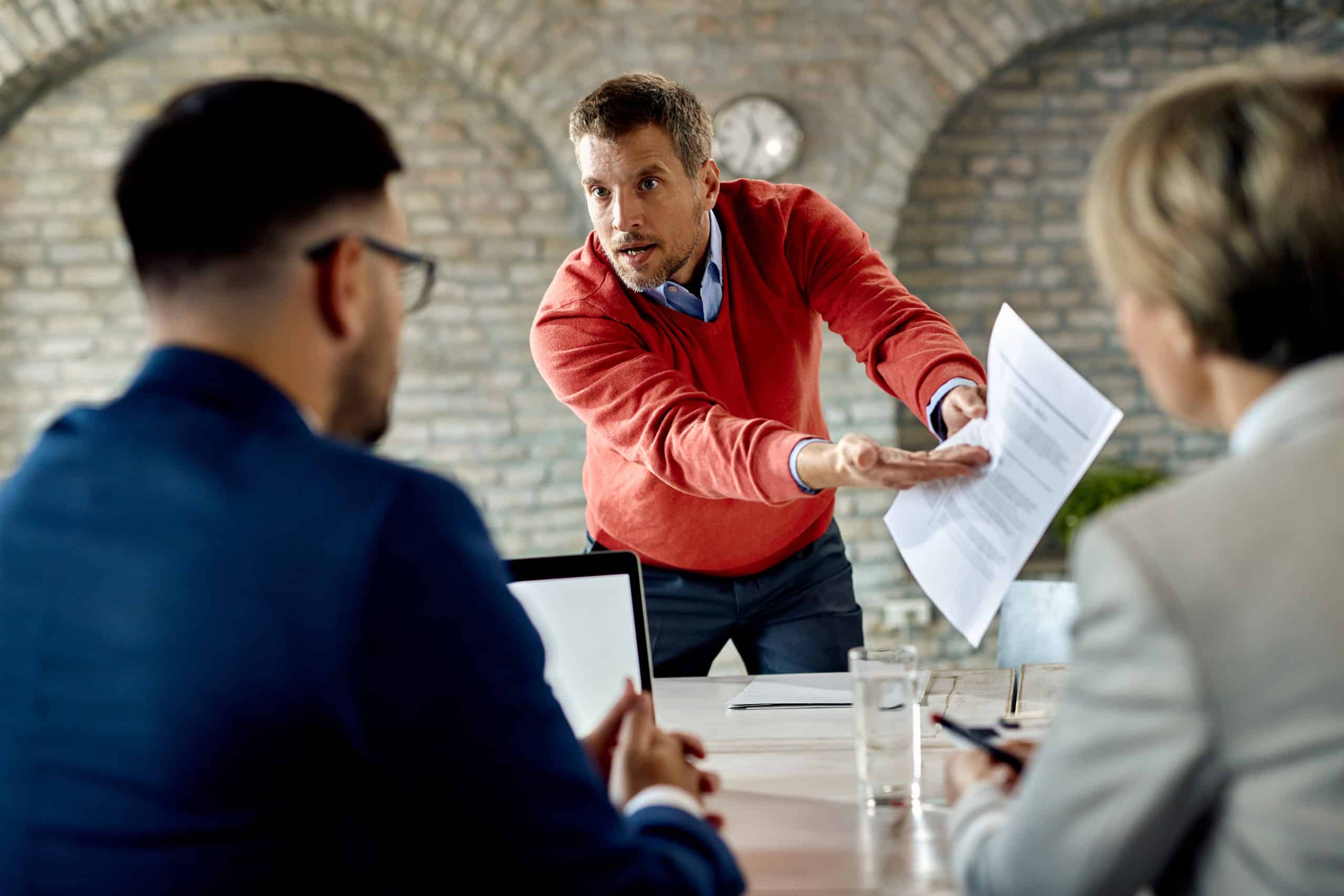 Candidat mécontent discutant de son CV avec l'équipe des ressources humaines lors d'un entretien d'embauche au bureau.