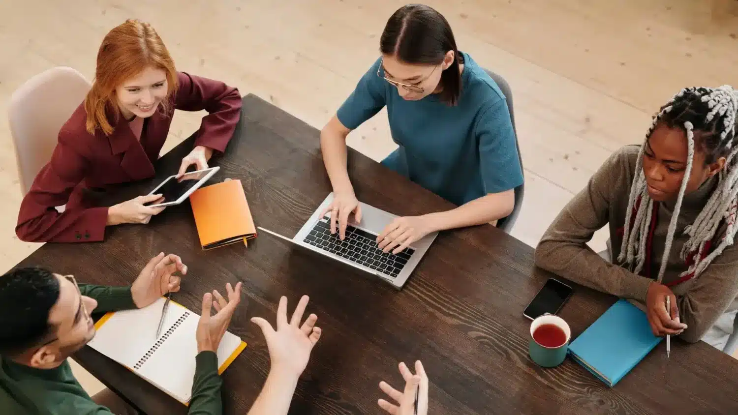 Groupe de jeunes en réunion autour d'une table travaillant sur un ordinateur