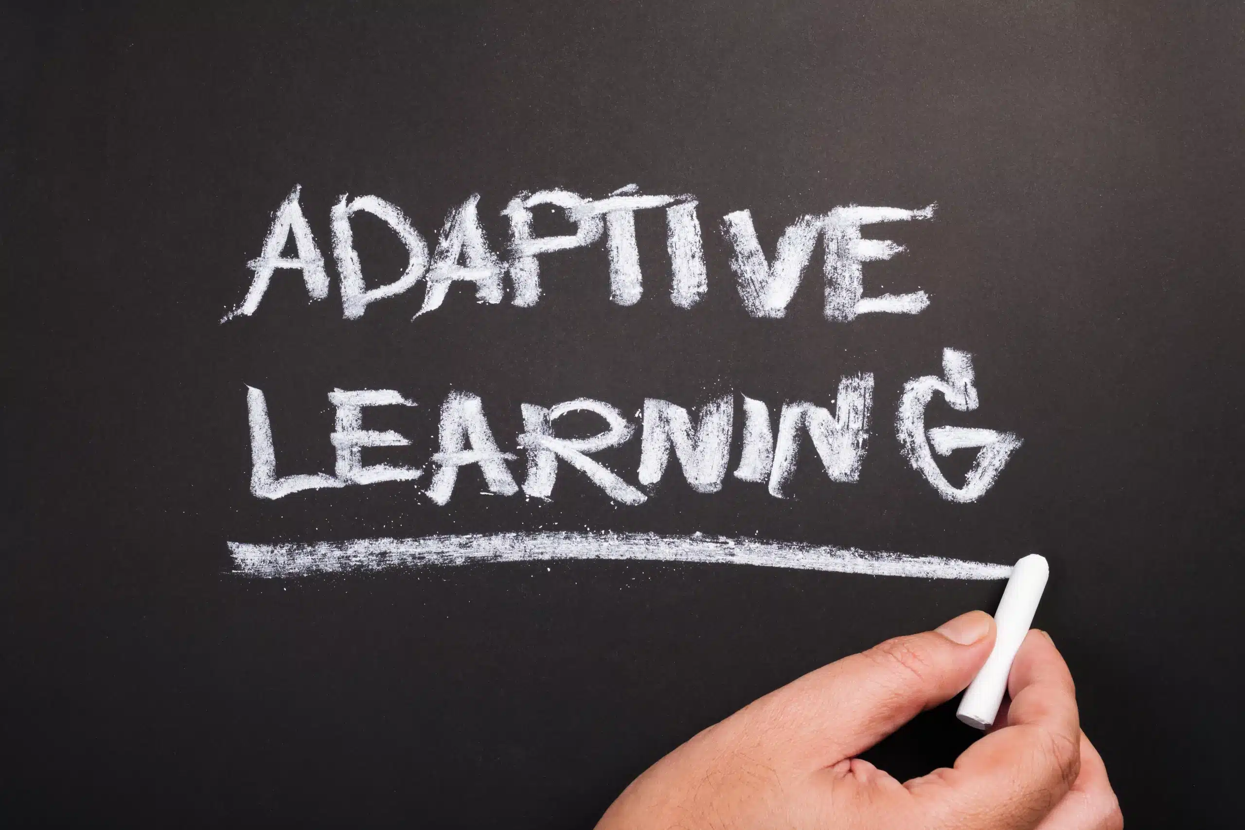 Texte 'Adaptive Learning' écrit à la craie sur un tableau noir.