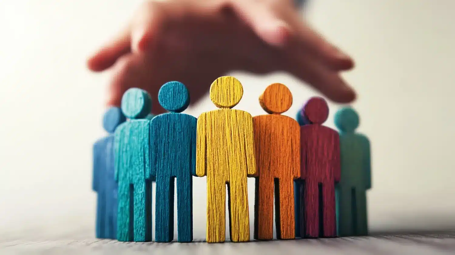 Une main surplombant des personnages en bois de couleur différente
