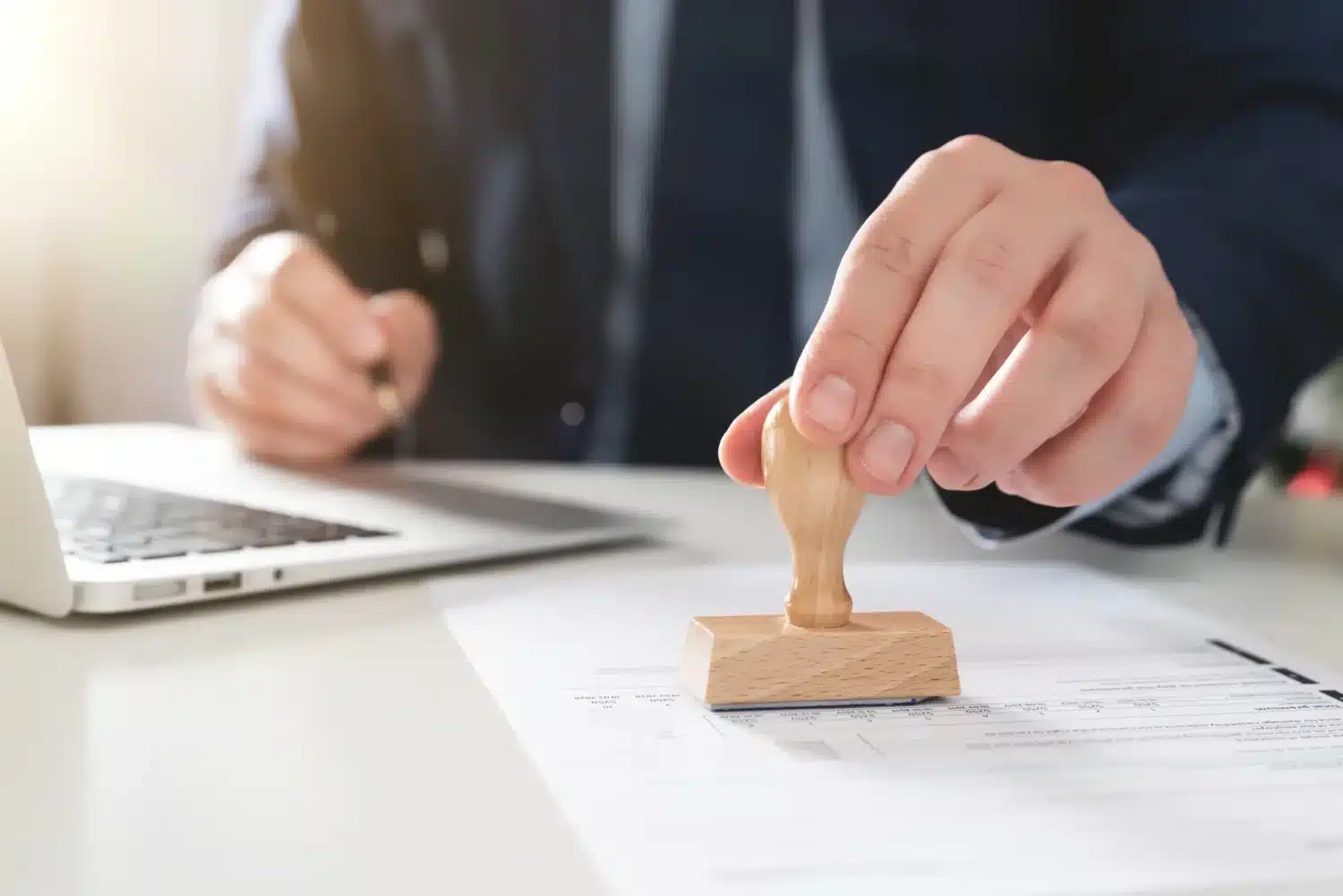 Main apposant un tampon officiel sur un contrat, symbolisant la conformité Qualiopi