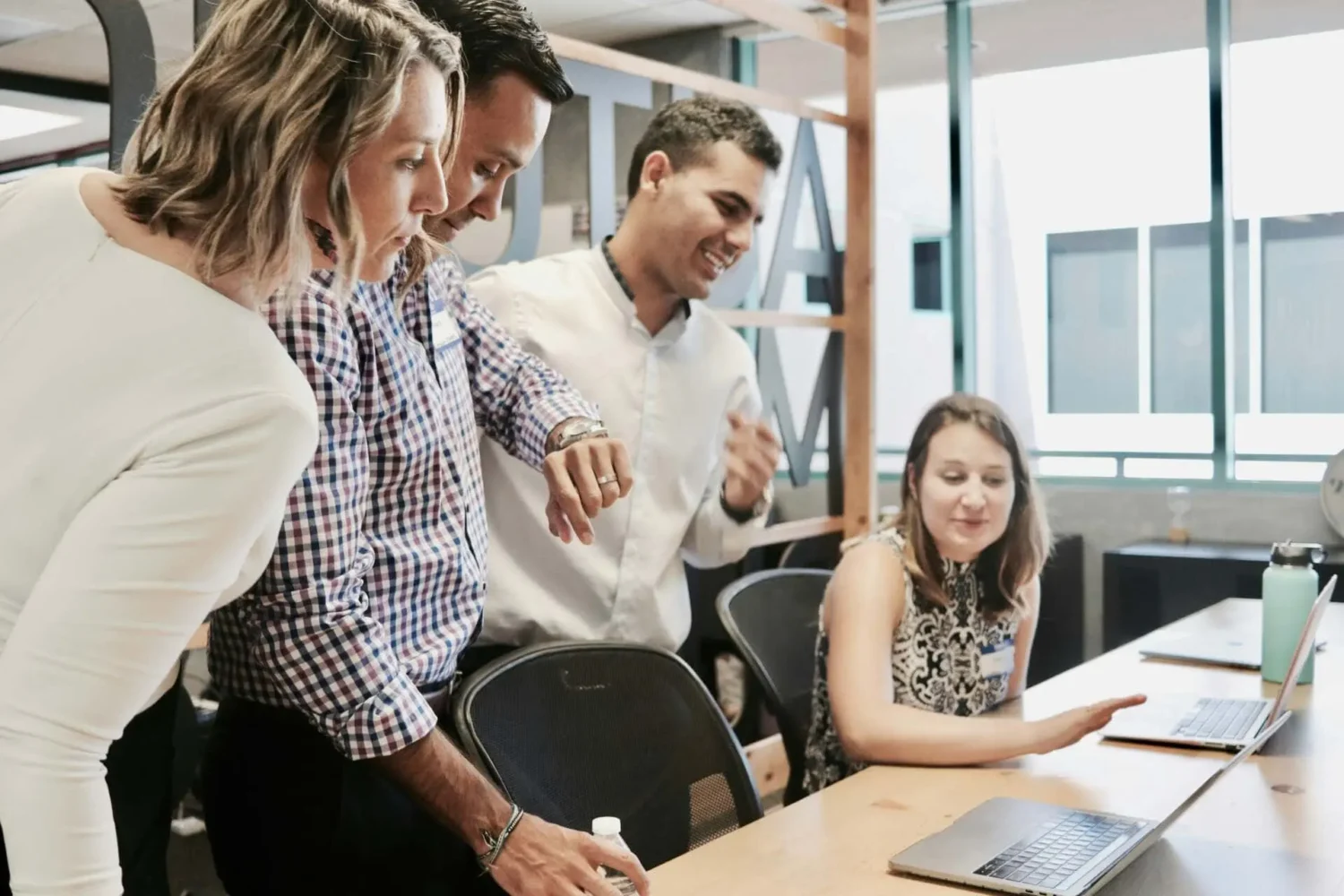 Groupe de professionnels collaborant autour d’un ordinateur dans un bureau lumineux.
